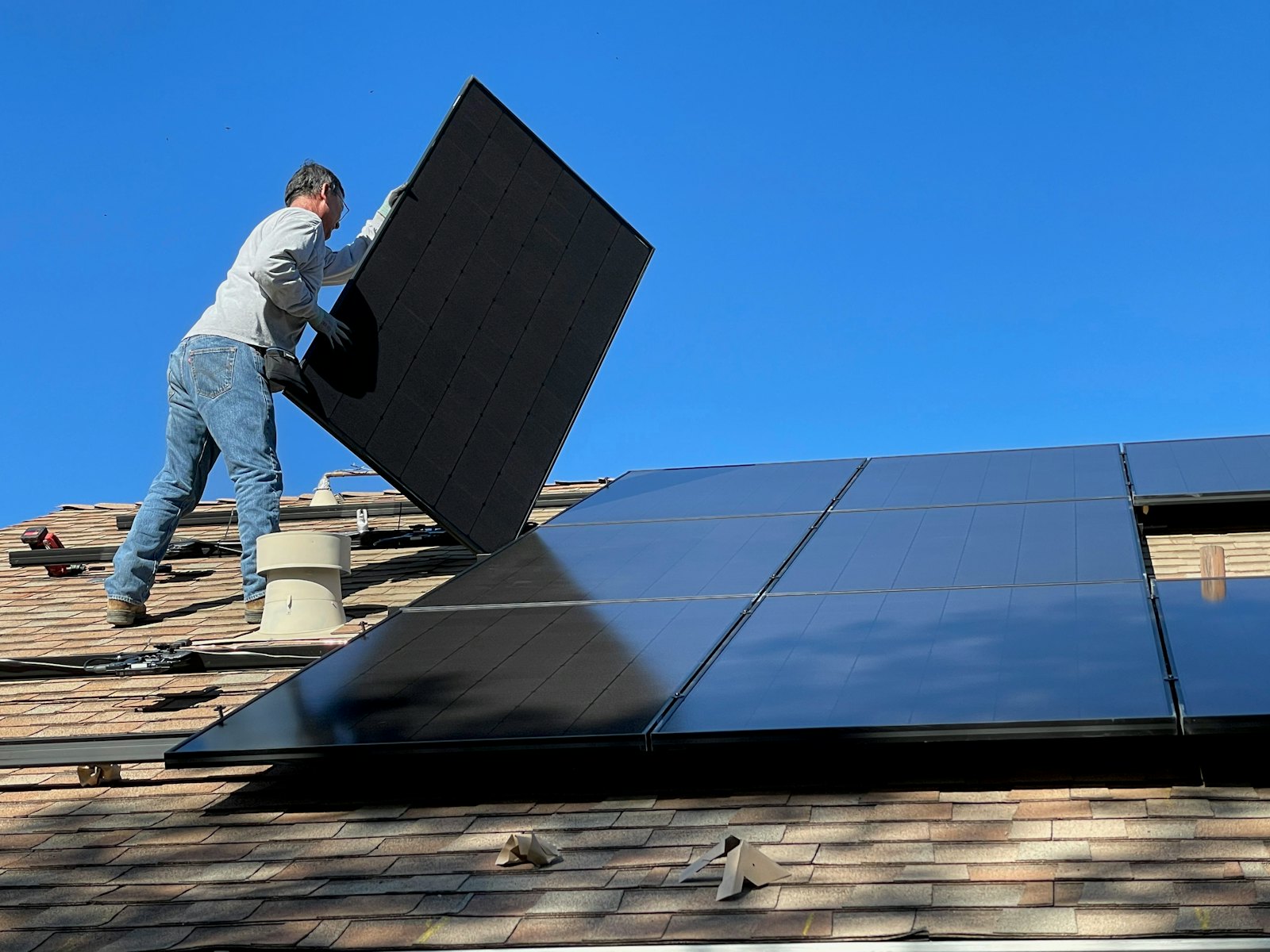 Instalador posicionando placa solar no telhado